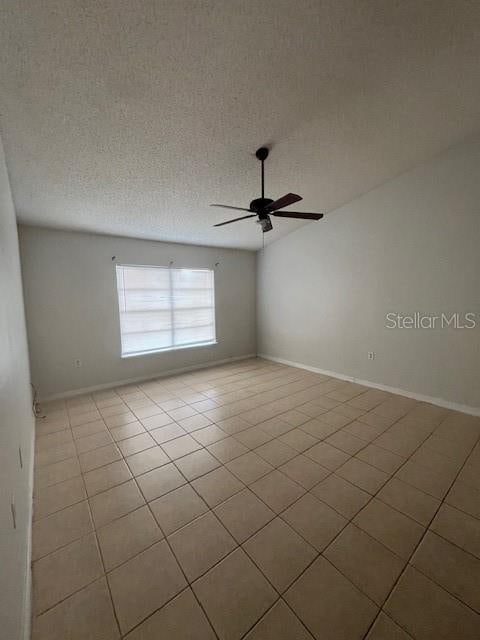 unfurnished room with ceiling fan, light tile patterned floors, and a textured ceiling