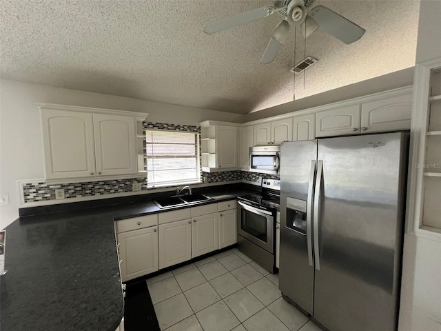 kitchen featuring white cabinets, appliances with stainless steel finishes, decorative backsplash, and sink