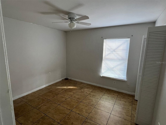 tiled spare room with ceiling fan