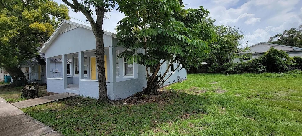 view of side of property featuring a porch and a lawn