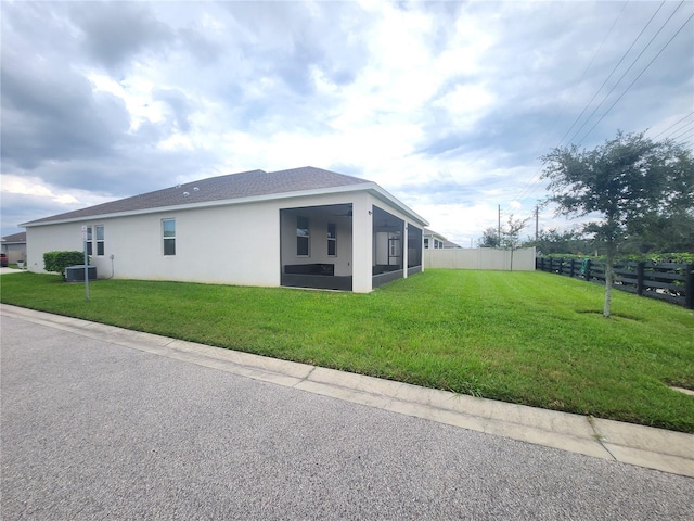 view of home's exterior with a yard, a sunroom, and central AC