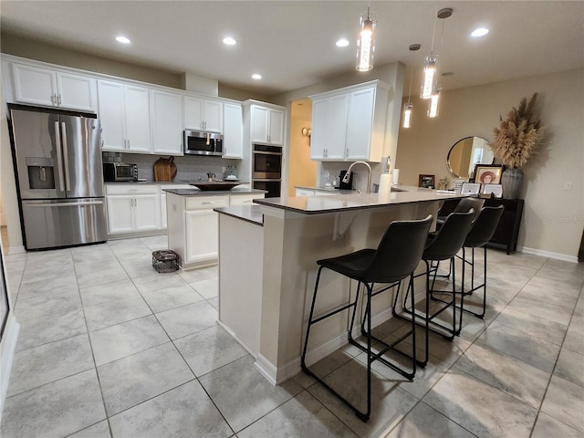 kitchen with pendant lighting, white cabinets, kitchen peninsula, stainless steel appliances, and a breakfast bar area