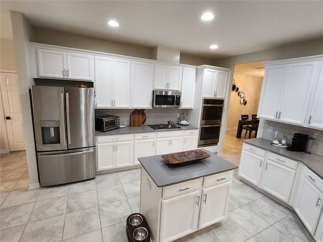 kitchen featuring appliances with stainless steel finishes, white cabinetry, light tile patterned floors, and tasteful backsplash