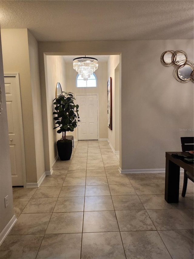 entryway with a notable chandelier, light tile patterned floors, and a textured ceiling