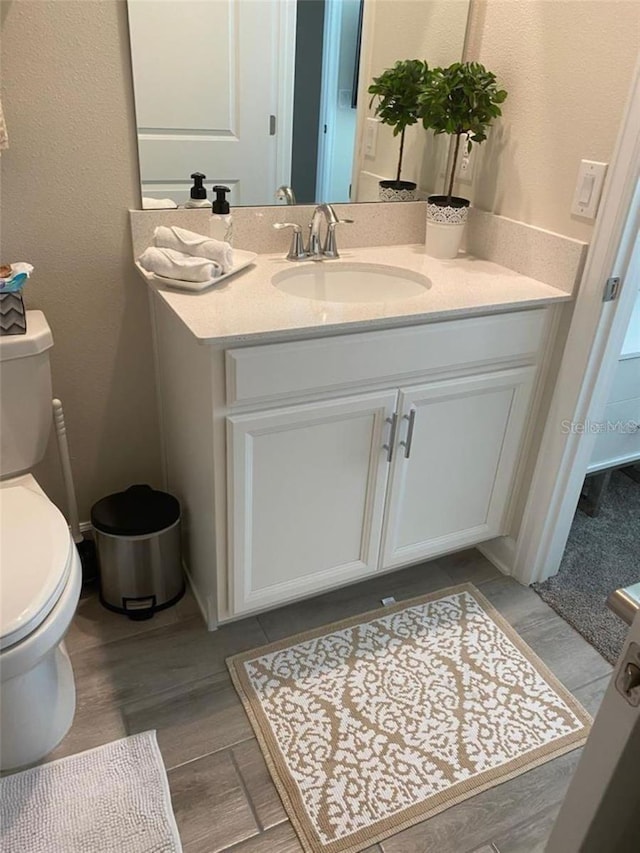 bathroom with toilet, wood finished floors, and vanity