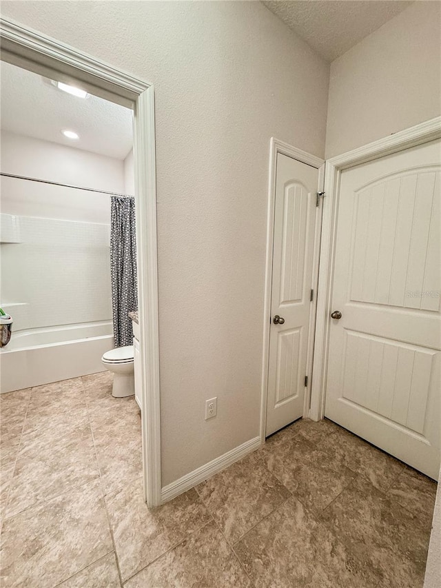 bathroom featuring shower / bath combination with curtain and toilet