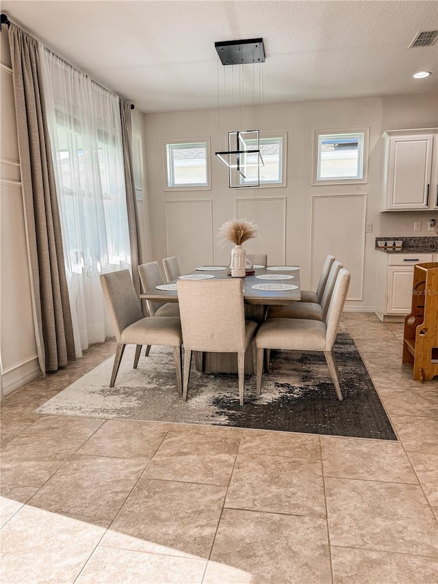 tiled dining space with a textured ceiling and a wealth of natural light