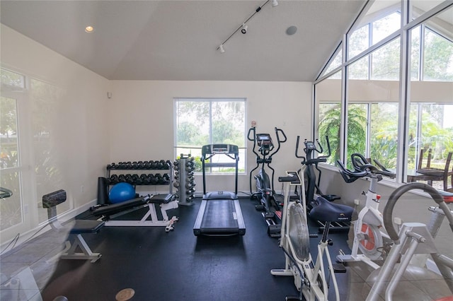 gym with a textured ceiling, rail lighting, and lofted ceiling