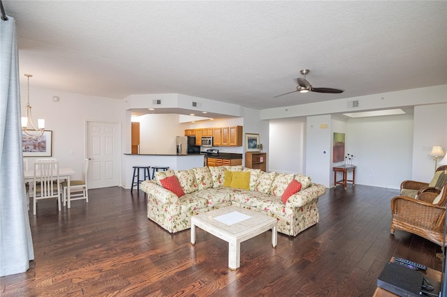 living room with ceiling fan with notable chandelier, a textured ceiling, and hardwood / wood-style floors