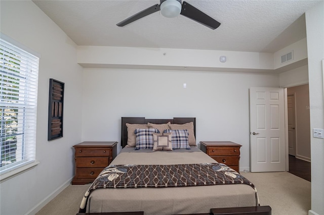 carpeted bedroom with ceiling fan and a textured ceiling