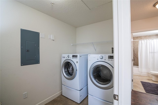 clothes washing area with dark hardwood / wood-style floors, washer and clothes dryer, a textured ceiling, and electric panel