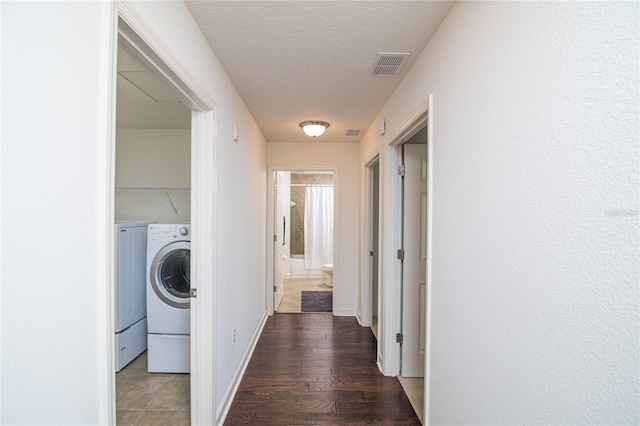 washroom with washing machine and clothes dryer, a textured ceiling, and dark hardwood / wood-style floors