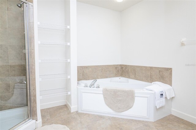 4177 N Orange Blossom Trl Unit 210, Orlando, FL 32804 - full bath featuring a shower stall, a bath, a walk in closet, tile patterned flooring, and baseboards