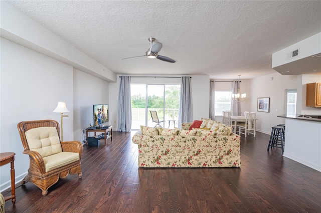 living room with ceiling fan with notable chandelier, a textured ceiling, and dark wood-type flooring