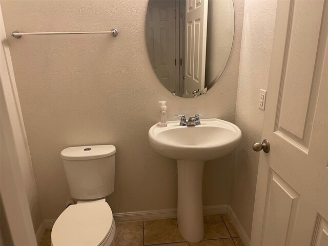 bathroom with toilet, sink, and tile patterned flooring