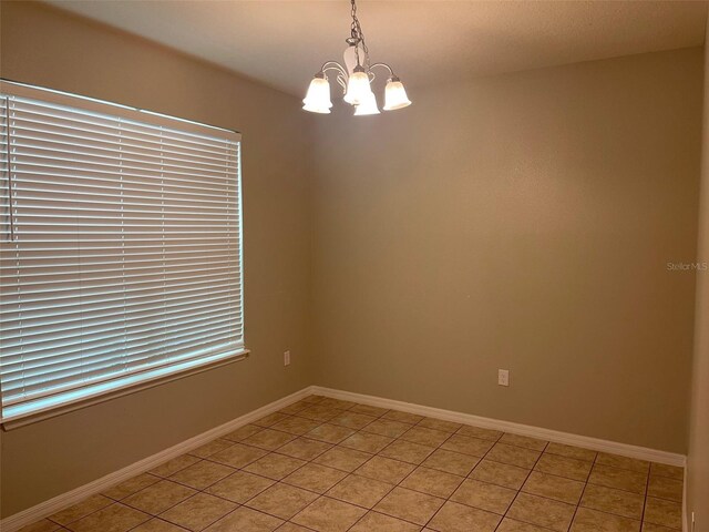 empty room featuring tile patterned flooring and a chandelier