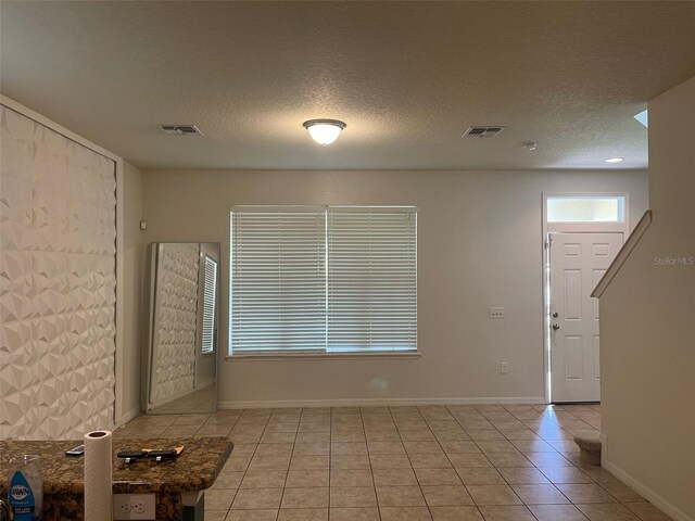 interior space with a textured ceiling and light tile patterned floors