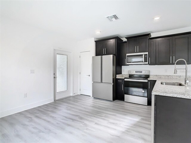 kitchen featuring light hardwood / wood-style flooring, stainless steel appliances, sink, and light stone countertops