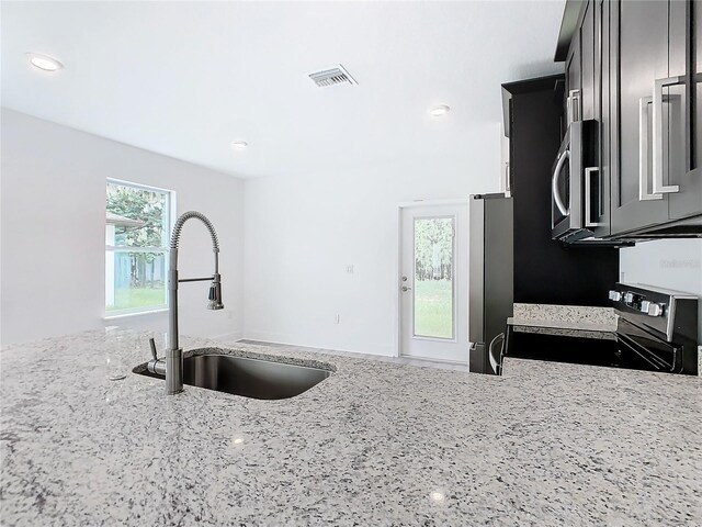 kitchen with appliances with stainless steel finishes, light stone countertops, and sink