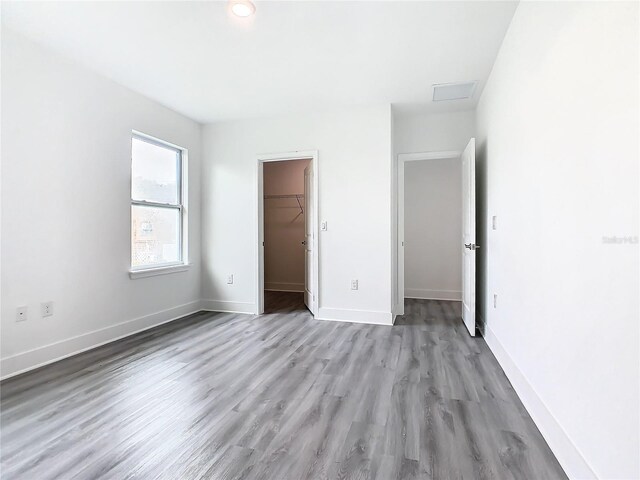 unfurnished bedroom featuring a walk in closet, a closet, and light hardwood / wood-style floors