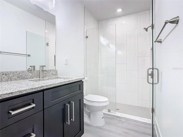 bathroom featuring walk in shower, toilet, wood-type flooring, and vanity