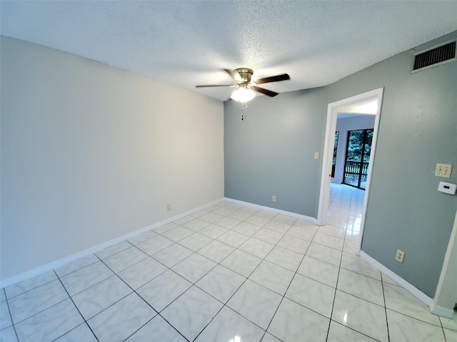 spare room featuring ceiling fan, light tile patterned flooring, and a textured ceiling