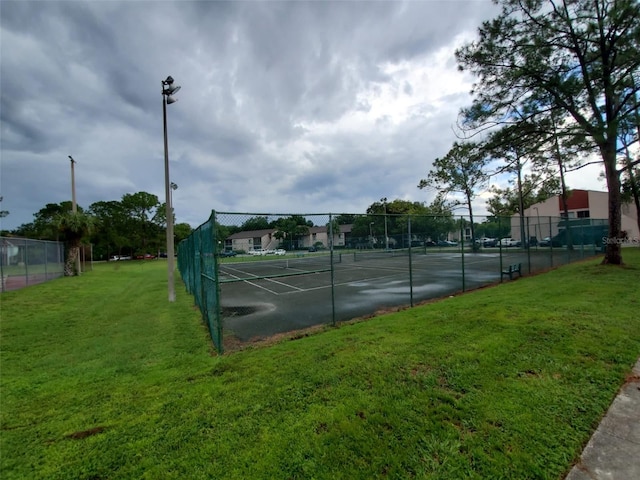 view of tennis court with a yard