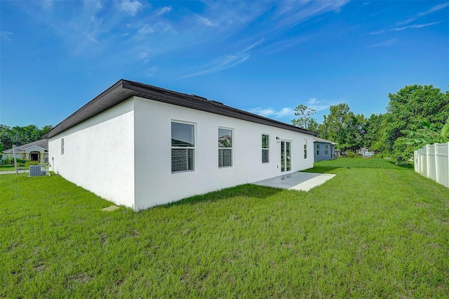 rear view of house featuring central AC unit, a patio area, and a yard