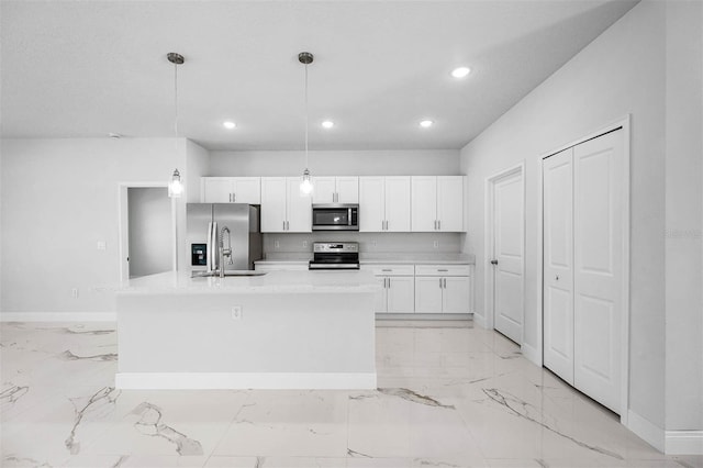 kitchen with white cabinetry, appliances with stainless steel finishes, a kitchen island with sink, decorative light fixtures, and sink