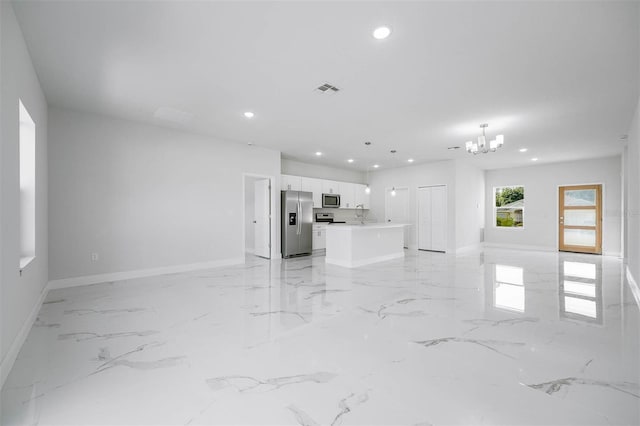 unfurnished living room featuring sink and a chandelier