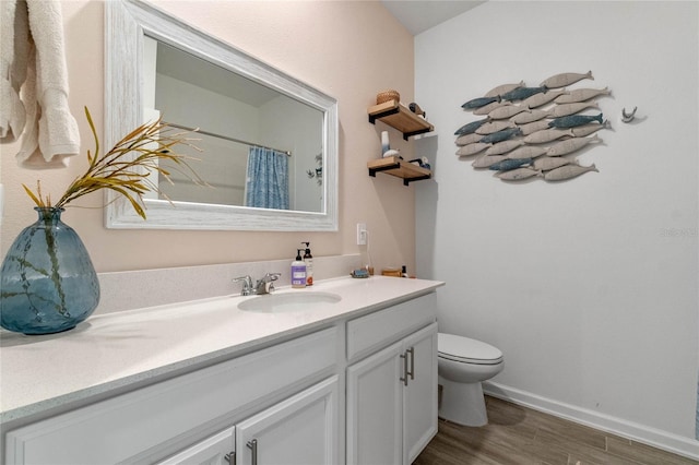 bathroom with wood-type flooring, walk in shower, vanity, and toilet