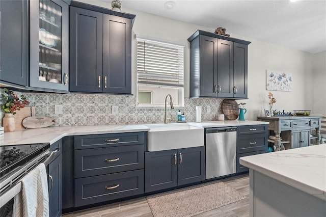 kitchen with light hardwood / wood-style floors, appliances with stainless steel finishes, tasteful backsplash, and sink