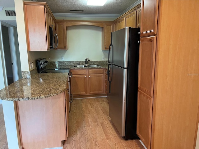 kitchen featuring sink, kitchen peninsula, a textured ceiling, light hardwood / wood-style flooring, and stainless steel appliances