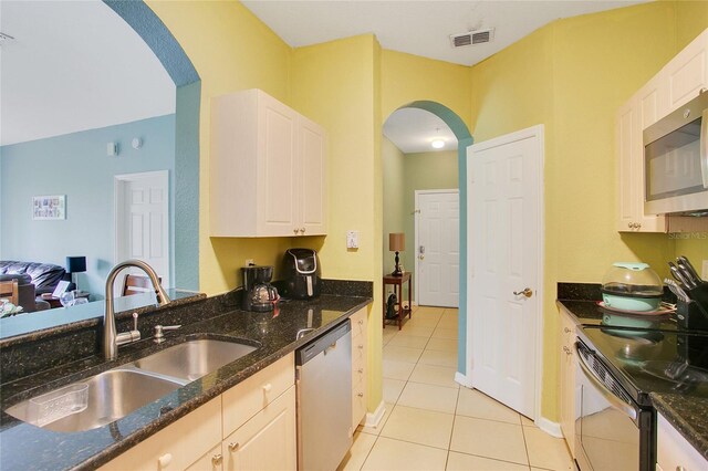 kitchen featuring dark stone countertops, white cabinets, appliances with stainless steel finishes, and sink