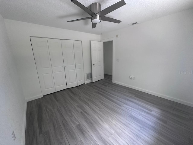 unfurnished bedroom featuring ceiling fan, dark hardwood / wood-style floors, a closet, and a textured ceiling