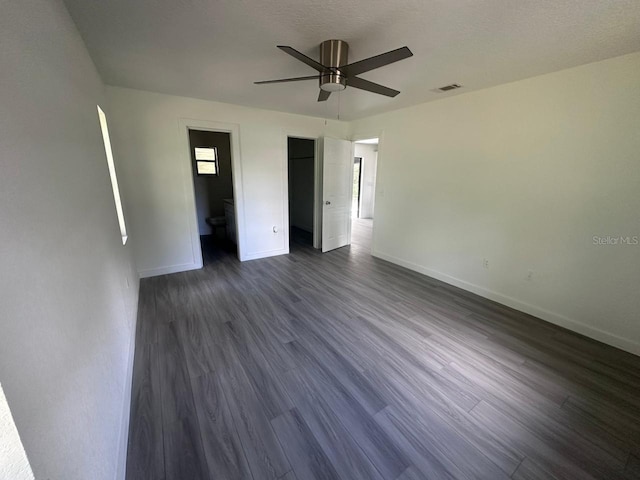 unfurnished bedroom with a textured ceiling, dark wood-type flooring, and ceiling fan