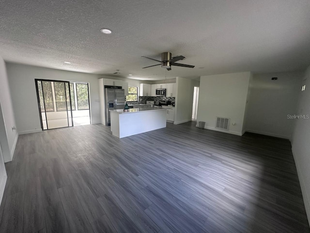 unfurnished living room featuring dark hardwood / wood-style flooring, a textured ceiling, and ceiling fan