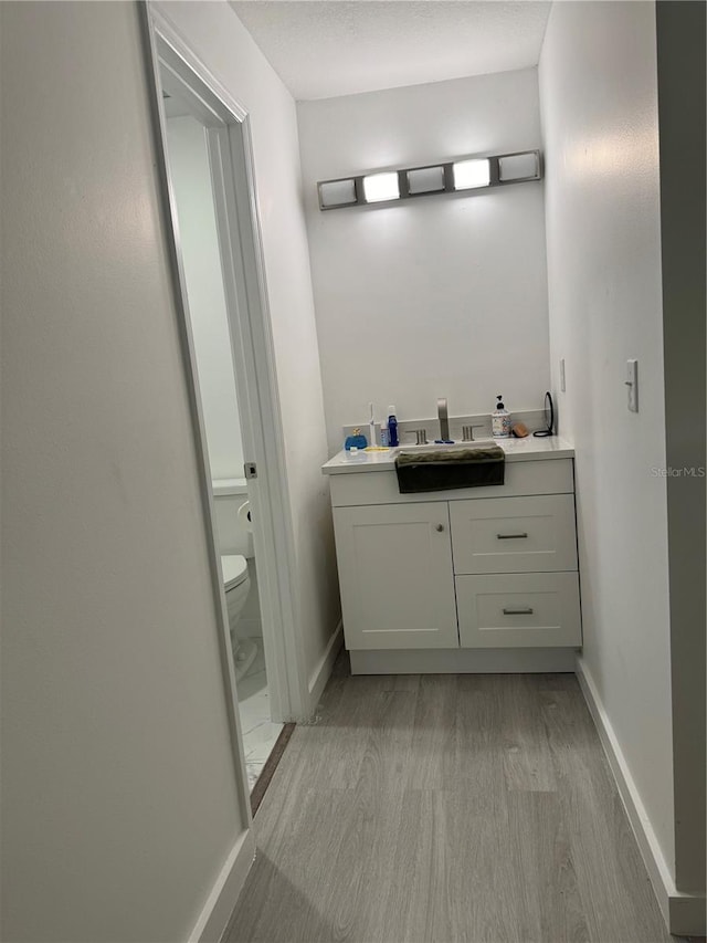 bathroom featuring wood-type flooring, vanity, and toilet