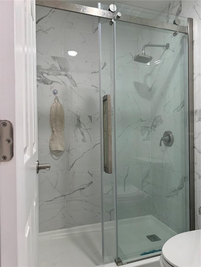 bathroom featuring walk in shower and toilet