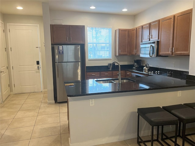 kitchen featuring a kitchen bar, kitchen peninsula, sink, and stainless steel appliances