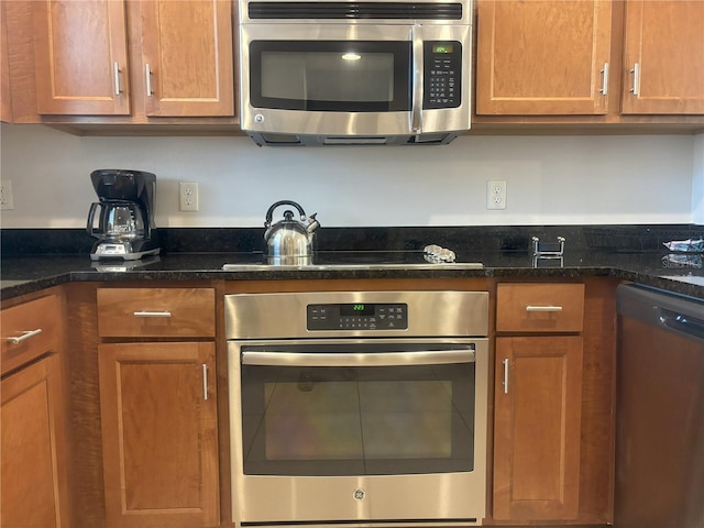 kitchen with appliances with stainless steel finishes and dark stone counters