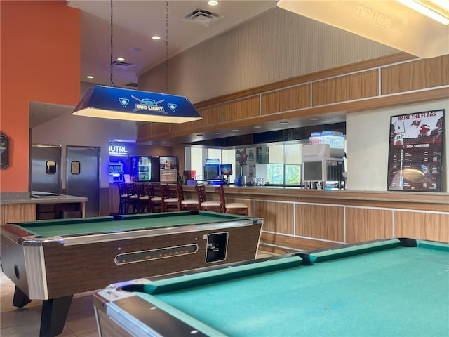 game room with a high ceiling, light tile patterned flooring, pool table, and indoor bar