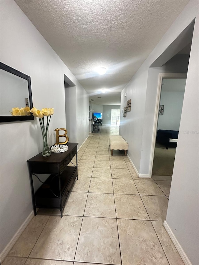 corridor with a textured ceiling and light tile patterned floors