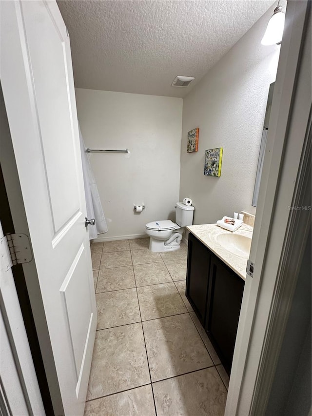 bathroom featuring a textured ceiling, tile patterned flooring, vanity, and toilet