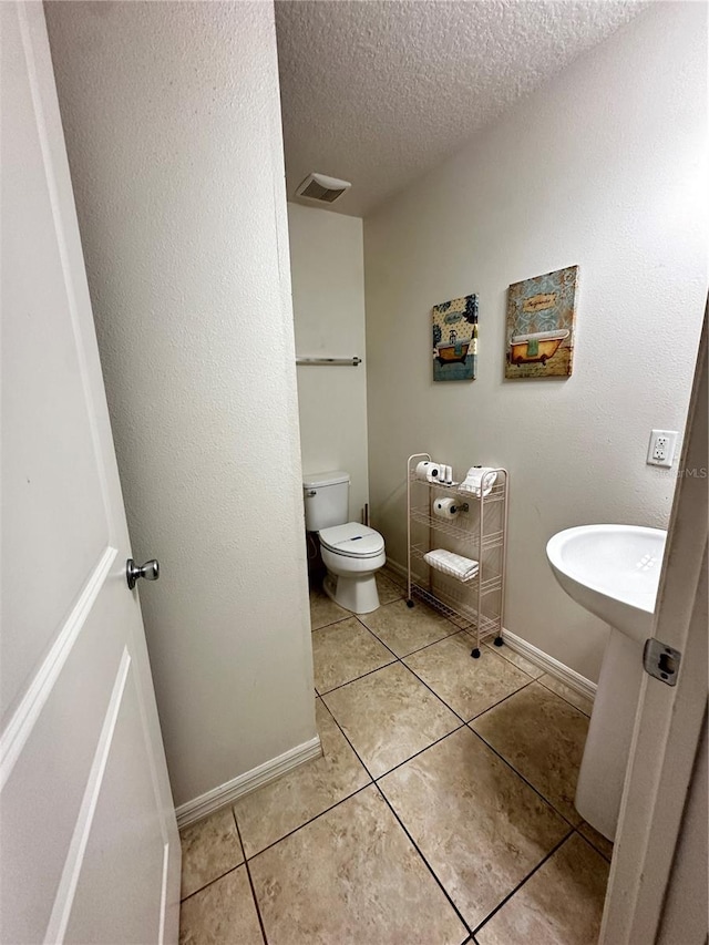 bathroom featuring a textured ceiling, toilet, and tile patterned floors