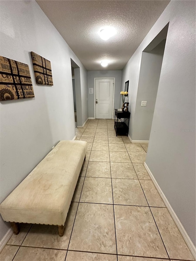 hall with a textured ceiling and tile patterned flooring