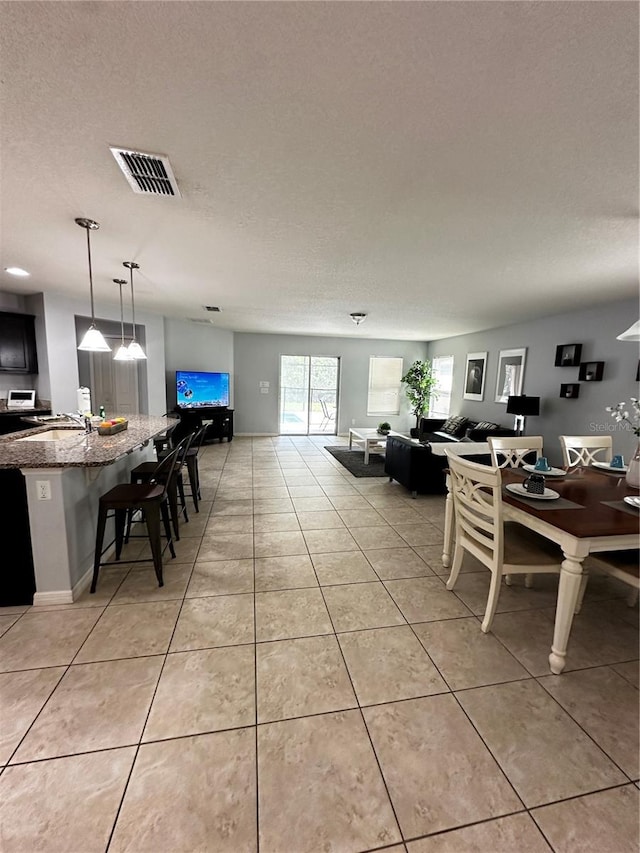 tiled dining room featuring a textured ceiling and sink