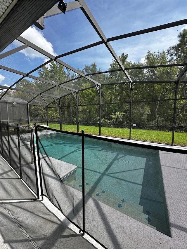 view of pool with glass enclosure and a lawn