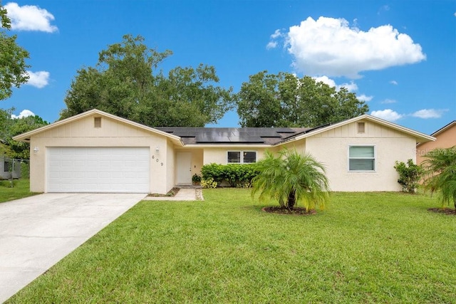 ranch-style home with a garage, a front lawn, and solar panels