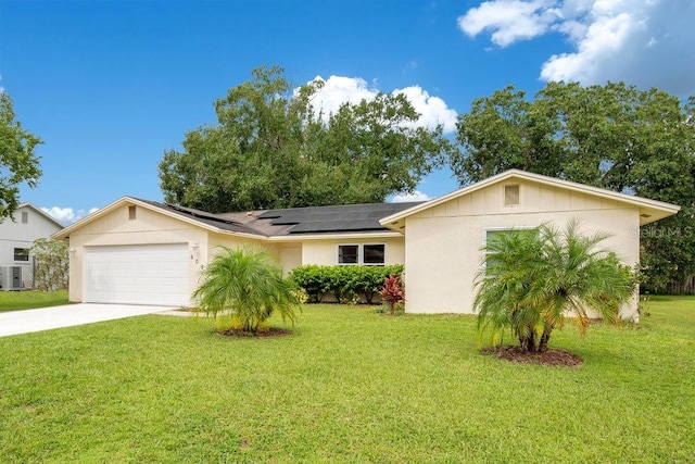 ranch-style house featuring a front yard, a garage, solar panels, and central air condition unit